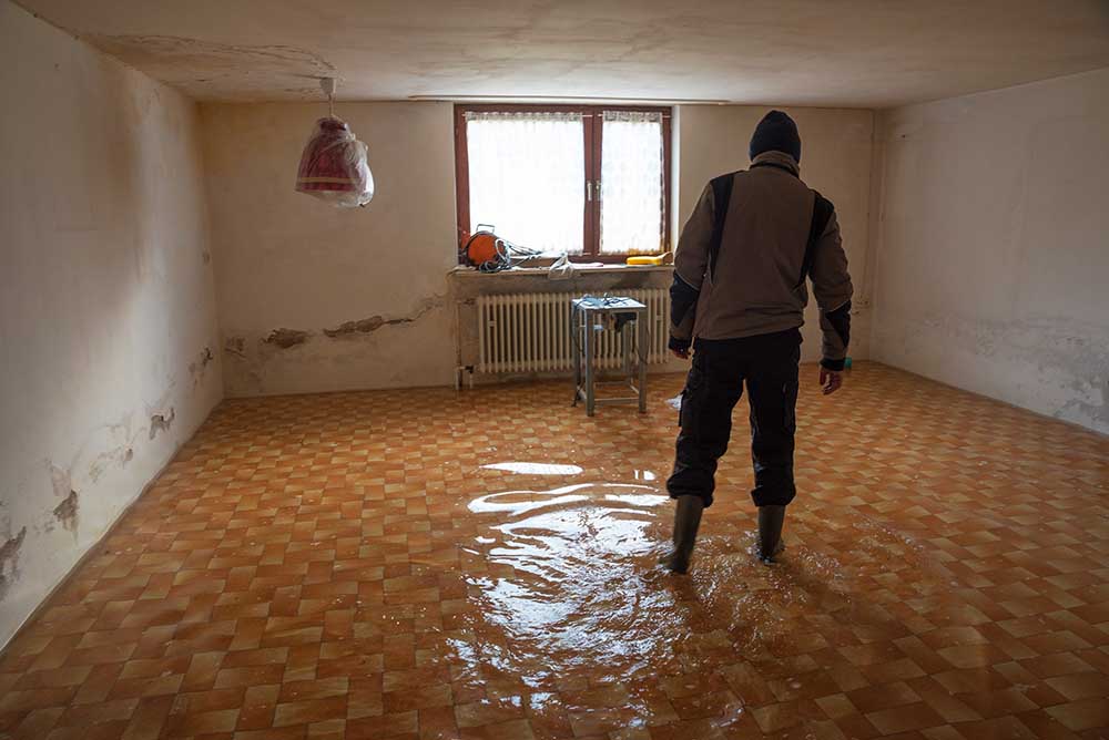 E.R. Services technician walking through a flooded room with poor drainage